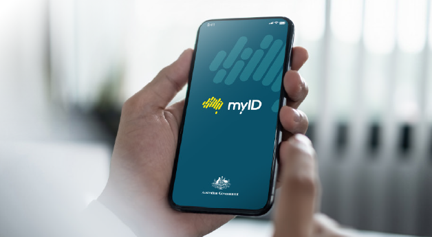 A hand holding a smartphone which displays the myID logo.